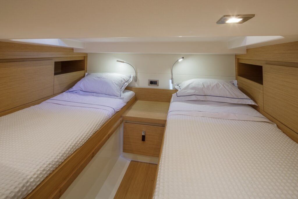 Bright and modern interior of Wai, featuring a master cabin with a double bed and a second cabin with twin beds.